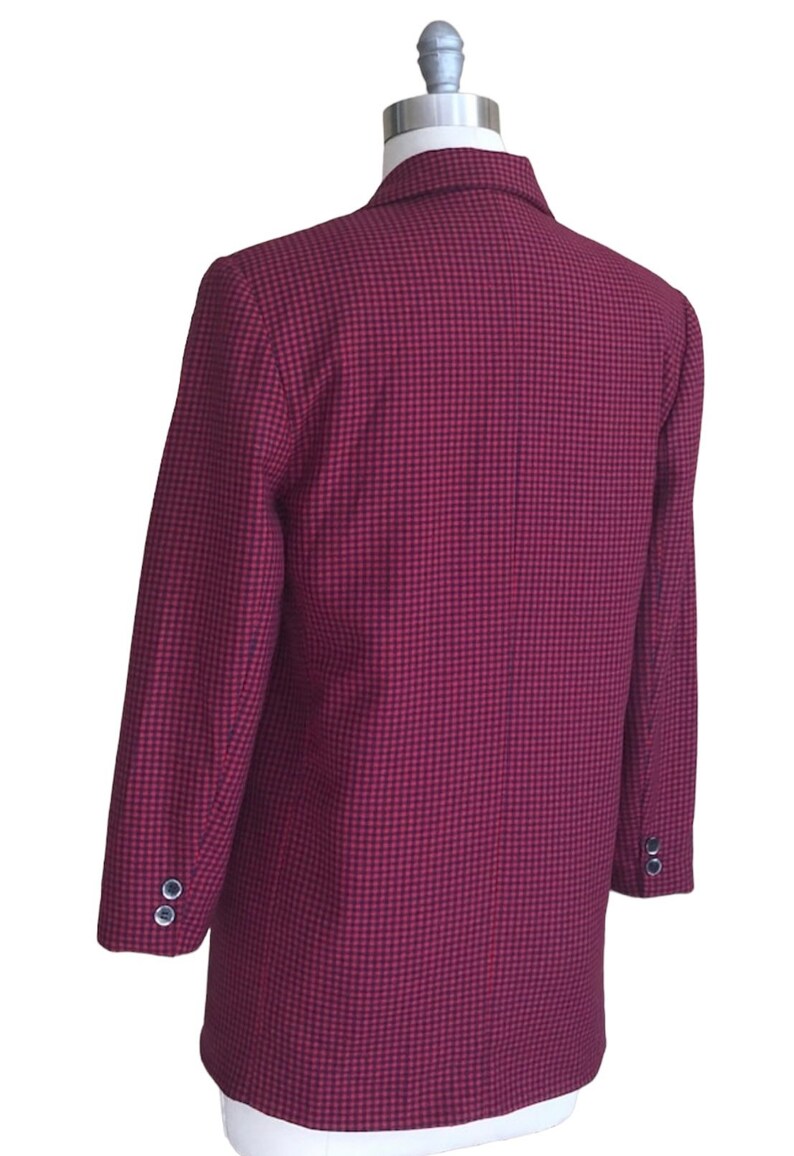 May include: A red and black checkered blazer with a single button closure. The blazer has long sleeves and a classic fit.