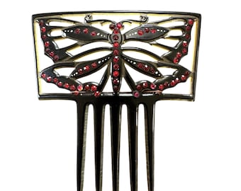May include: A black metal hair comb with a butterfly design. The butterfly is decorated with red rhinestones.