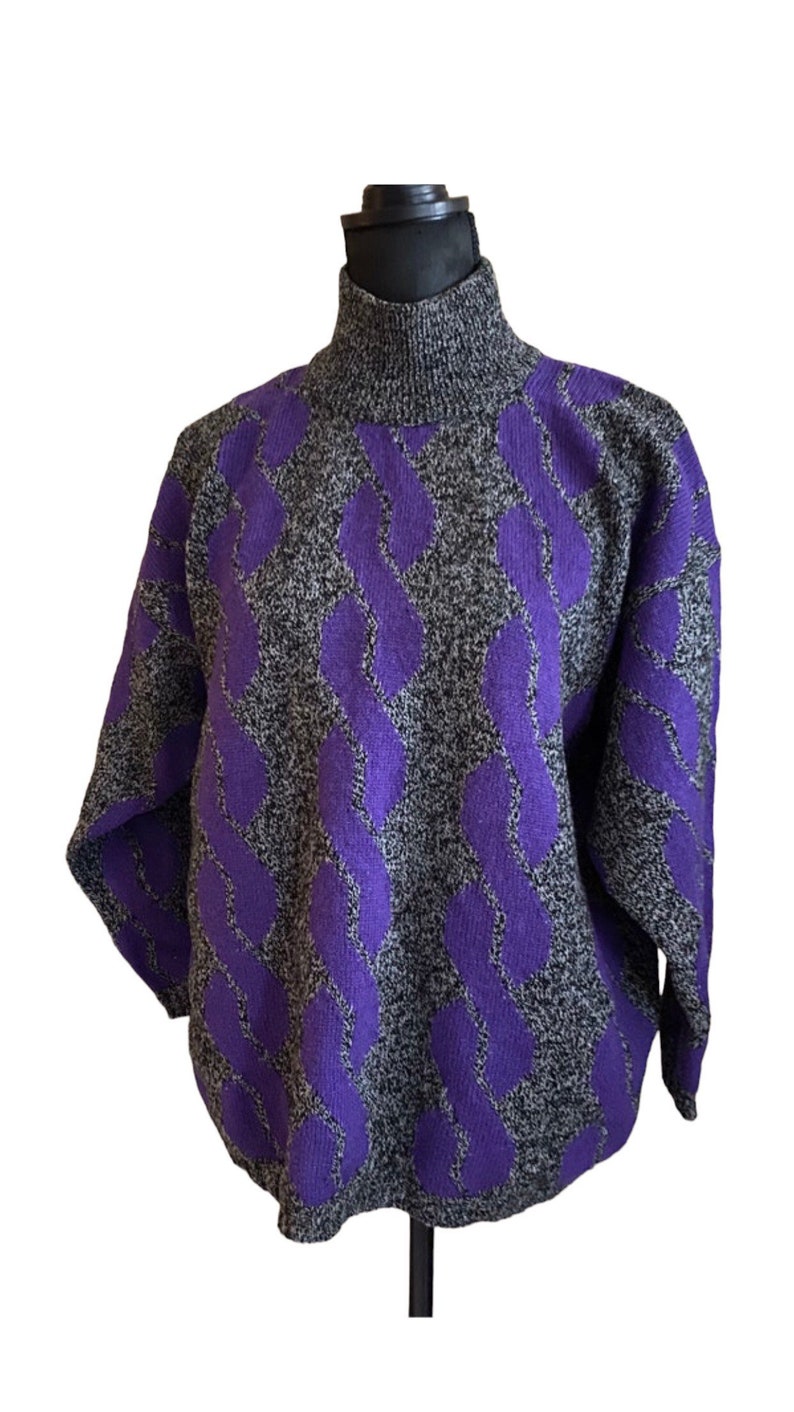 May include: A gray and black turtleneck sweater with a repeating purple pattern. The sweater is displayed on a mannequin and has long sleeves. The pattern is a series of vertical, interconnected, wavy lines.