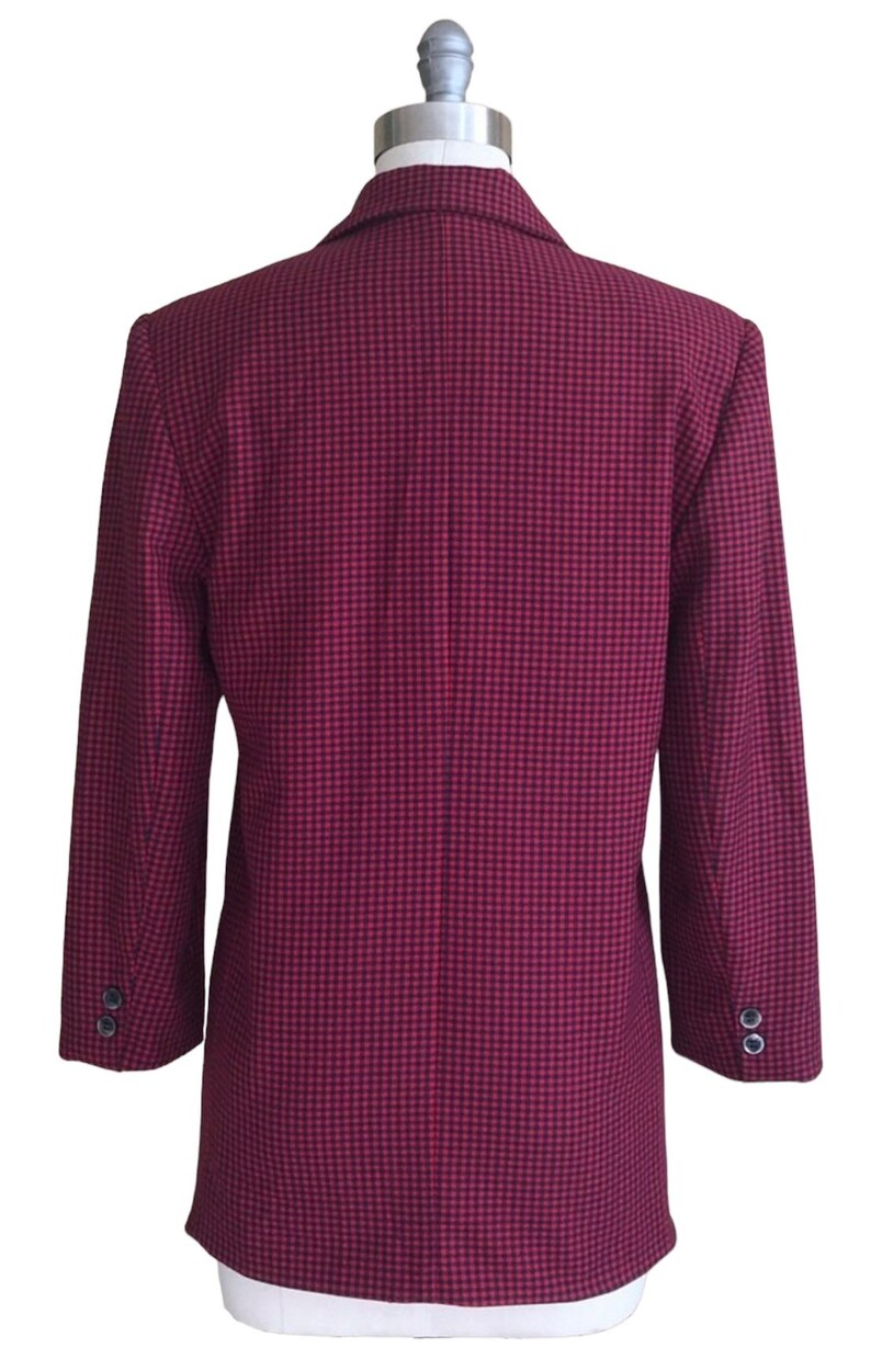 May include: A red and black checkered blazer with long sleeves and a single button closure. The blazer is on a white mannequin.