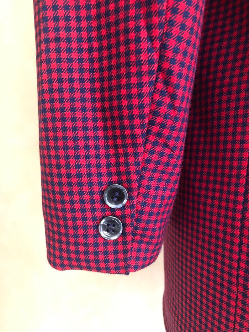 May include: Red and black gingham blazer with two black buttons on the sleeve.