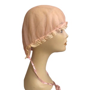 May include: A pink nylon sleeping cap with a lace trim and a pink satin ribbon tie.