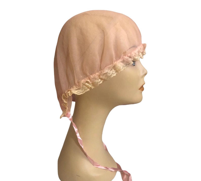 May include: A pink nylon sleeping cap with a lace trim and a pink satin ribbon tie.