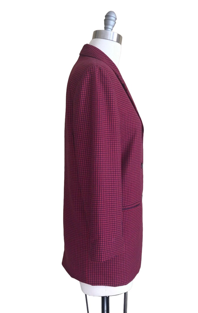 May include: A red and black checkered blazer with a double breasted closure and a single pocket on the left side.