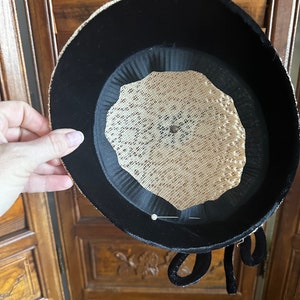 May include: Black velvet hat with a beige mesh lining and a black velvet bow. The hat has a pin in the center.