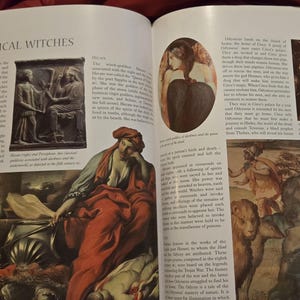 May include: An open book with the title "THE CLASSICAL WITCHES" on the top left. The pages display various illustrations and text, including images of classical art and paintings. The book is open on a dark surface.