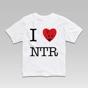 May include: White t-shirt with the text "I" and "NTR" in black, with a red heart featuring an anime-style character. The heart is above the "NTR" text. The shirt is a short-sleeved crew neck.