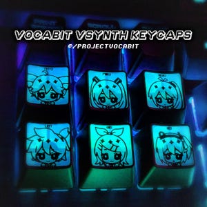 May include: Illuminated VOCABIT VSYNTH keycaps with anime character designs. The keycaps feature glowing illustrations of anime characters with names like Teto, Miku, and Rin. The text "VOCABIT VSYNTH KEYCAPS" and "@PROJECTVOCABIT" are displayed on the image.