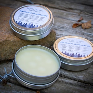 May include: Two silver tins of beard balm with a label that reads "Dry Hollow Farm Beard Balm Patchouli Sandalwood" and "Net Wt. 4 oz (113g)".