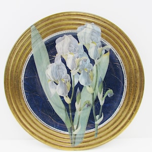 May include: A decorative plate with a gold rim and a blue background featuring a white iris flower design.