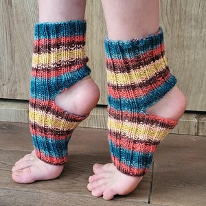 May include: A pair of colorful knitted leg warmers. The leg warmers are striped with teal, yellow, orange, and brown. The design includes a cutout for the heel and toes, and the warmers are worn on the lower legs.