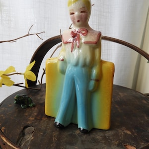 May include: A white ceramic mug with a black handle and the text "But First, Coffee" in a handwritten style. The mug is on a white surface. The mug is approximately 4 inches tall.