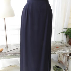 May include: A long, dark blue skirt with a straight silhouette. The skirt is made of a smooth, wrinkle-resistant fabric.