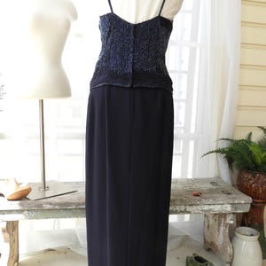 May include: A black formal gown with a beaded bodice and a long, flowing skirt. The bodice is a deep blue color with silver beads.
