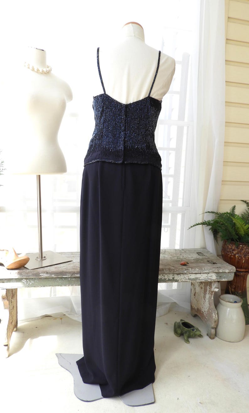 May include: A black formal gown with a beaded bodice and a long, flowing skirt. The bodice is a deep blue color with silver beads.