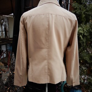 May include: A beige blazer with long sleeves and a button-up front. The blazer is made of a smooth, textured fabric.