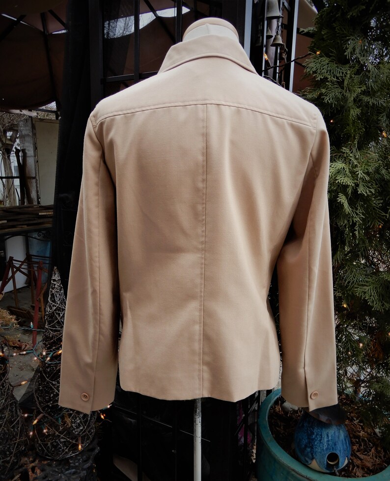 May include: A beige blazer with long sleeves and a button-up front. The blazer is made of a smooth, textured fabric.