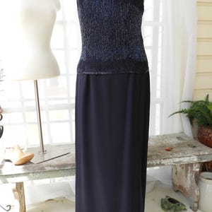 May include: A black sequined top with a matching black skirt. The top has a V-neckline and spaghetti straps. The skirt is floor-length and has a slit in the front.
