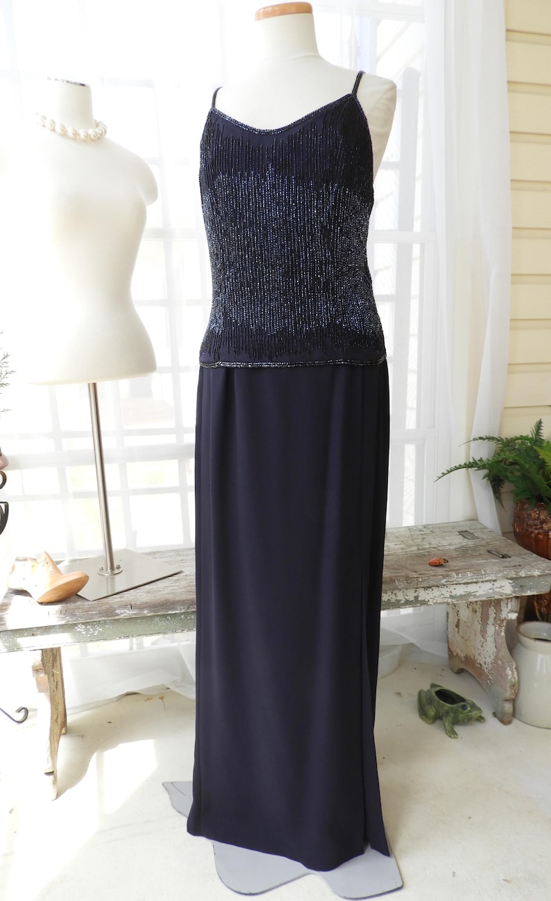 May include: A black sequined top with a matching black skirt. The top has a V-neckline and spaghetti straps. The skirt is floor-length and has a slit in the front.