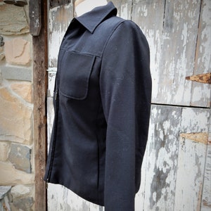 May include: A black zip-up jacket with a long sleeve and a single pocket on the left chest.
