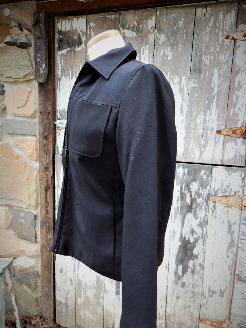 May include: A black zip-up jacket with a long sleeve and a single pocket on the left chest.