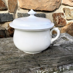 May include: White ceramic chamber pot with a lid. The pot has a rounded body and a single handle. The lid has a knob on top.