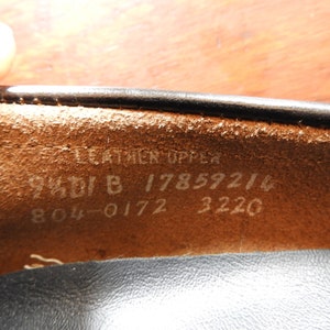 May include: Close-up of the inside of a black leather shoe. The insole is brown leather with white text that reads "Leather Upper 94DI B 17859214 804-0172 3220".