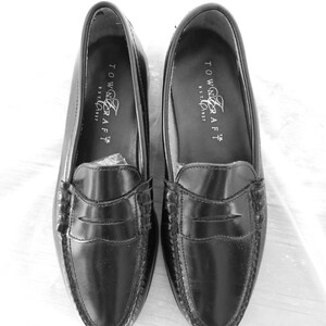 May include: A pair of black leather loafers with a penny strap detail. The loafers have a stitched edge and the brand name "Towncraft" is printed on the inside of each shoe.