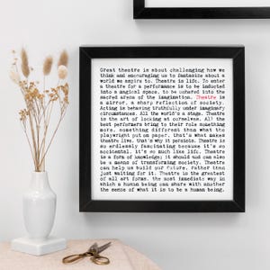 May include: A framed black and white print with the text "Great theatre is about challenging how we think and encouraging us to fantasize about a world we aspire to." The print is in a black frame.