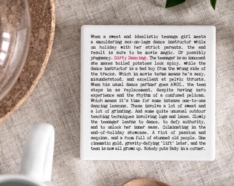 May include: A white square coaster with black text describing the plot of the movie "Dirty Dancing". The text is centered and in a sans-serif font. The coaster is on a light-colored surface.