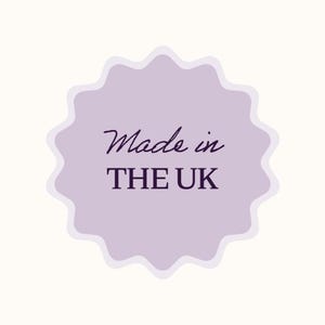 K&ouml;nnte beinhalten: Ein helllila Aufkleber mit gewelltem Rand und den Worten "Made in THE UK" in dunkelvioletter Schrift und serifenloser Schriftart. Der Aufkleber ist vor einem cremefarbenen Hintergrund platziert.