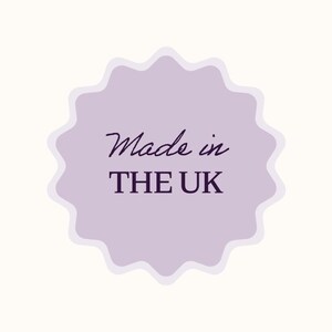 Puede incluir: Una pegatina morada clara con borde festoneado con las palabras "Made in THE UK" en una fuente oscura p&uacute;rpura y sin serifa. La pegatina est&aacute; sobre un fondo de color crema.