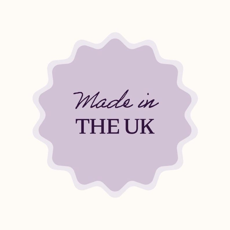 May include: A light purple, scalloped-edge sticker with the words "Made in THE UK" in a dark purple script and sans-serif font. The sticker is set against a cream-colored background.