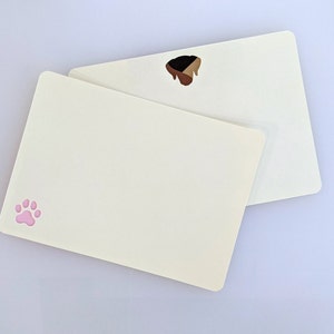 May include: Two blank white cards with rounded corners. The top card has a brown paw print. The bottom card has a pink paw print.
