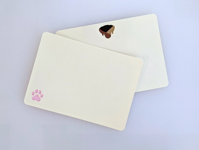 May include: Two blank white cards with rounded corners. The top card has a brown paw print. The bottom card has a pink paw print.