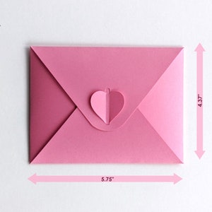 Op de afbeelding: Een roze papieren envelop met een hartvormige sluiting. De envelop is 14,6 cm breed en 11,1 cm hoog. De hartsluiting heeft een lichtere roze tint. De envelop is gesloten.