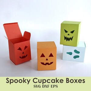 Könnte beinhalten: Vier Halloween-Cupcake-Boxen mit verschiedenen ausgeschnittenen Kürbisgesichtern. Die Boxen sind orange, rot, grün und blau. Der Text "Spooky Cupcake Boxes" befindet sich am unteren Rand des Bildes.