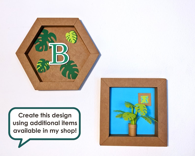 May include: Two brown paper frames with a blue background. The first frame is a hexagon with a green monstera leaf design and the letter "B" in the center. The second frame is a square with a green monstera plant in a brown pot.