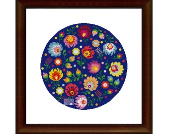 May include: A round, blue cross-stitch pattern with colorful flowers and leaves. The design is framed in a dark brown wood frame.