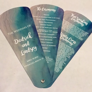 May include: A wedding ceremony program fan with a watercolor background in shades of blue and green. The program includes the order of events for the wedding ceremony, foot washing ceremony, and unity cross ceremony. The wedding is for Diedrick and Lindsey on April 30, 2016, in Pensacola Beach, Florida.