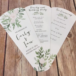 May include: A white wedding program fan with a floral design. The program includes the wedding ceremony order, the wedding party, and the wedding date and location. The text reads "The Wedding of Carly & Ian, August 27, 2016, Agoura Hills, CA."