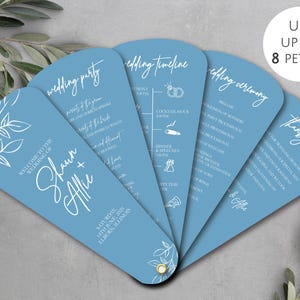 May include: A collection of light blue wedding fan programs with white text and floral designs. The programs are fanned out, showcasing wedding details and a thank you message. The text includes the names "Shawn + Allie".