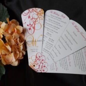May include: A wedding program fan with a floral design in shades of pink, orange, and white. The fan has multiple panels with text for the wedding ceremony, the wedding party, and a thank you message. The text includes the names "Anthony & Mike" and the date "June 29, 2013".