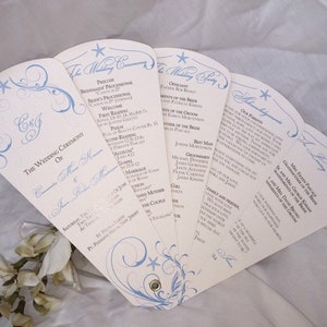 May include: A white wedding program fan with blue and silver accents. The fan features a floral design with a starfish at the top. The program includes the wedding ceremony order, the wedding party, and the family and friends. The text on the fan reads "The Wedding Ceremony of C & J" and "A Long, Happy Marriage".