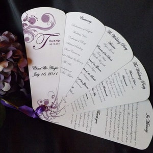 Könnte beinhalten: Ein weißer Hochzeitsfächer mit violetten Blumenmustern und dem Text "Chad & Angie July 16, 2011". Das Programm enthält Abschnitte für die Zeremonie, die Hochzeitsgesellschaft und einen Dank.