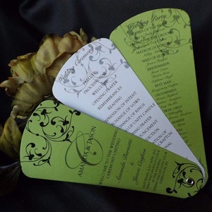 Könnte beinhalten: Grüne und weiße Hochzeitszeremonie-Fächer mit schwarzen und silbernen floralen Designs. Die Fächer enthalten die Namen Amanda & Jason, das Hochzeitsdatum und die Reihenfolge der Ereignisse für die Zeremonie und den Empfang.