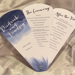 Könnte beinhalten: Ein Fächer mit einem Programm für eine Hochzeitszeremonie mit einem Aquarelldesign in Blautönen. Der Fächer zeigt die Namen "Diedrich und Lindsey" und das Datum "30. April 2016". Das Programm listet die Reihenfolge der Ereignisse für die Zeremonie und den Empfang auf, einschließlich des Präludiums, des Austauschs der Gelübde, des Kusses und der Cocktailstunde.