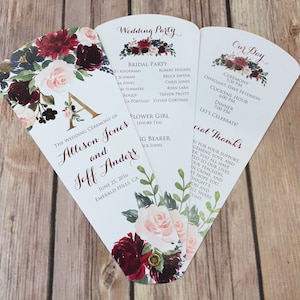 May include: A wedding program fan with a floral design in shades of burgundy, pink, and green. The program includes the wedding ceremony details for Allison Jones and Jeff Anders, the wedding party, and a special thanks section.