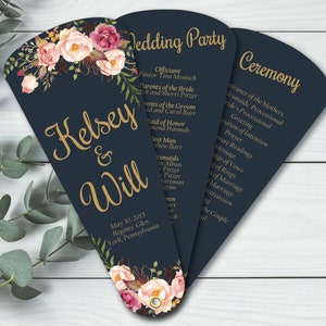 May include: A navy blue wedding program fan with a floral design and gold lettering. The program lists the wedding party and ceremony order. The text reads "Kelsey & Will" and "May 30, 2015, Regents Glen, York, Pennsylvania".