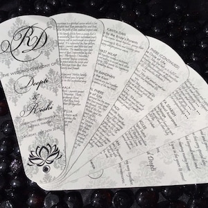 May include: A white wedding ceremony program fan with a silver and black floral design. The fan features the names "Deepti & Rishi" and the date "Saturday, July 26th 2014". The fan includes a list of wedding ceremony events, such as "Kanya Dan", "Hast Milap", "Phere", and "Pudi with Vows".